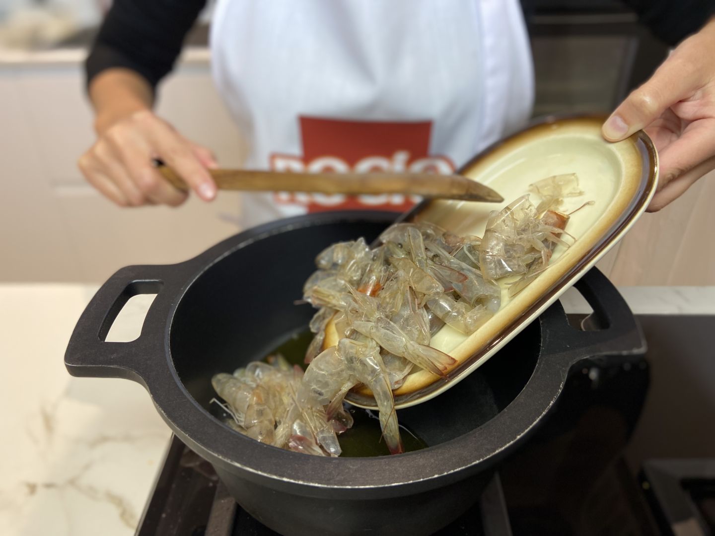 chef agregando gambas a olla